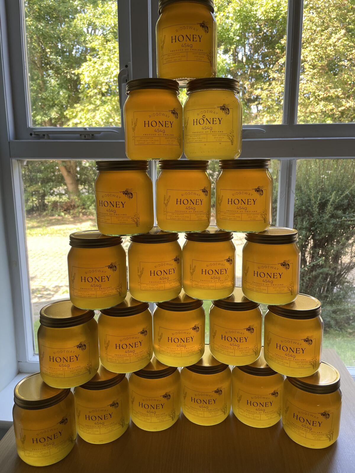 Jars of Ridgeway Honey stacked in a pyramid in front of a window